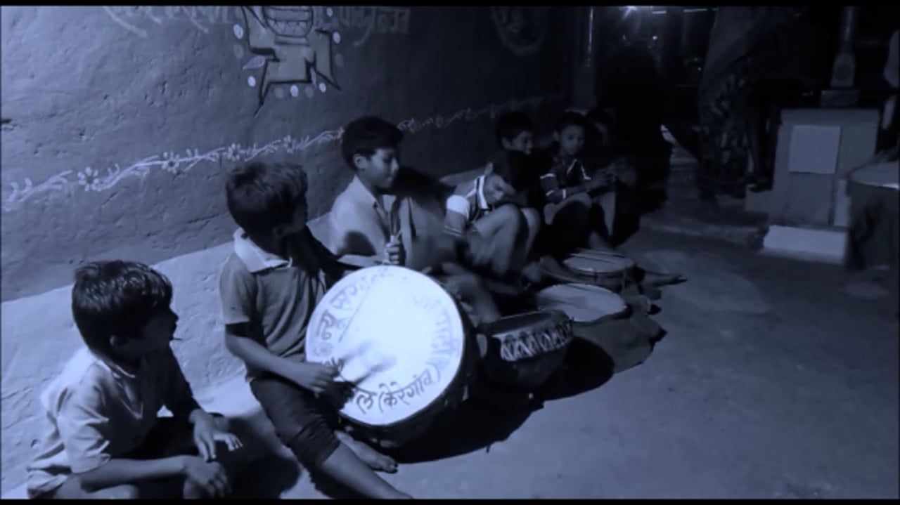 Still from Chinhari: The Young India — children seated together at night, one playing a drum